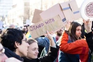 people standing in crowd holding signs to end the war in Ukraine